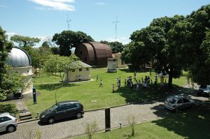 imagem aérea do gramado do campus com pessoas e o pavilhão restaurado ao fundo